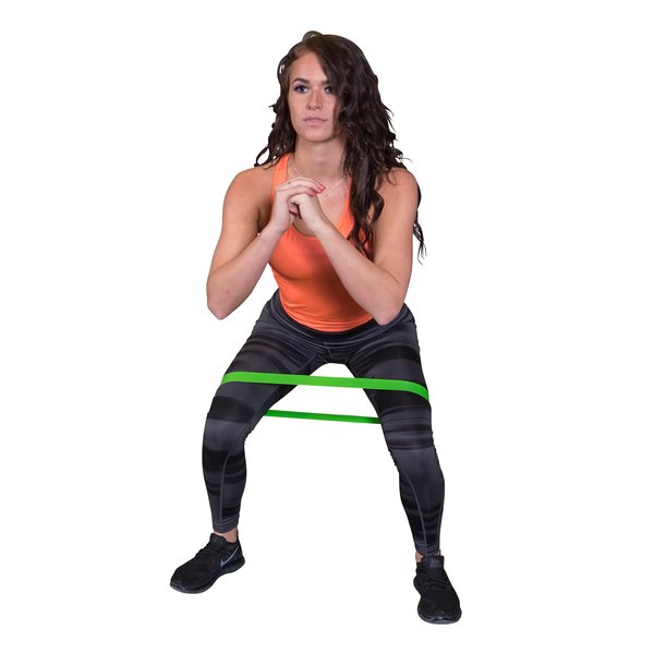 Female athlete performing a squat with green resistance bands for strength training.