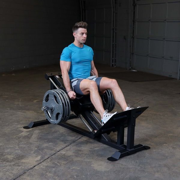 Side view of a user performing leg presses on the Body-Solid GCLP100, highlighting the adjustable seating and heavy-gauge steel frame.