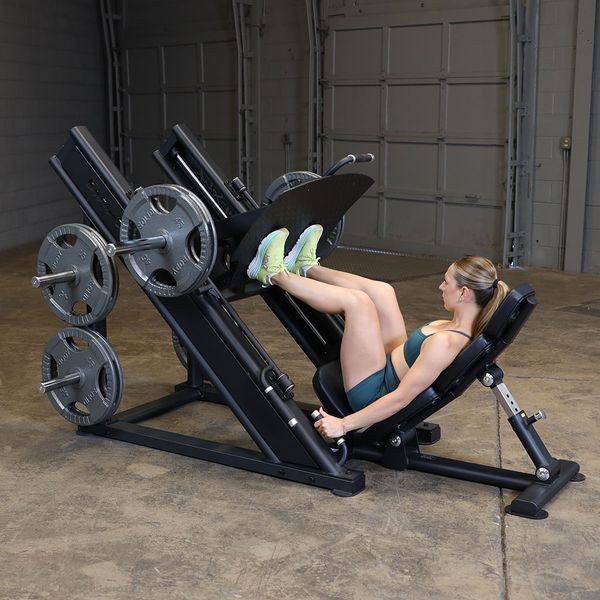 Athlete demonstrating the Body-Solid SGLP500 Leg Press from the right side, highlighting the fully loaded weight horns and large footplate.