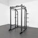 Side view of the BodyKore G703 Foundation Series Squat Cage showcasing the 3"x3" steel frame, multi-grip pull-up bar, dual landmines, J hooks, spotter bars, and weight storage pegs, designed for strength training in home or commercial gyms.