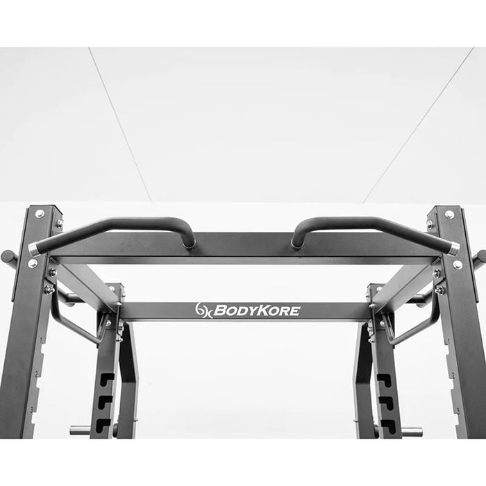 Close-up of the multi-grip pull-up bar at the front of the BodyKore G703 Foundation Series Squat Cage, highlighting textured grips and durable 3"x3" steel construction for versatile upper body workouts.