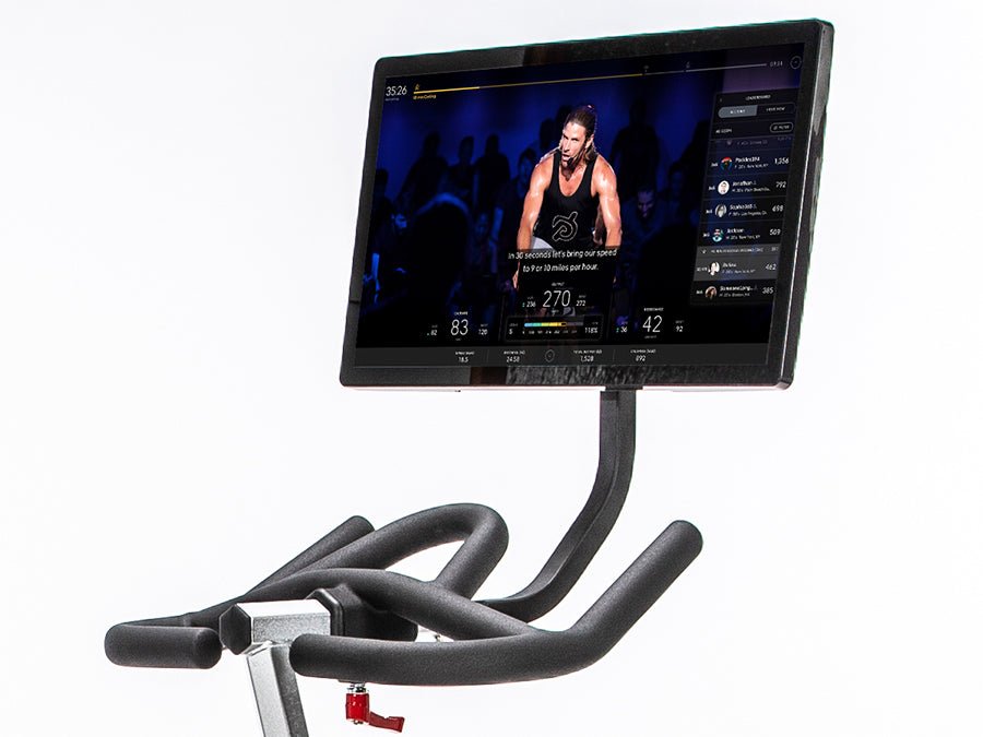 Connect-22 tablet mounted on a BodyCraft indoor cycle, displaying a fitness trainer leading a workout on screen.