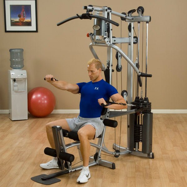 Male athlete performing chest press with alternating independent cables on the Powerline by Body-Solid P2X Home Gym, viewed from above to highlight cable movement and arm positioning.