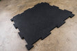 Close-up of interlocking black puzzle mats made of heavy-duty rubber, showcasing the puzzle-style edges for easy installation, designed to protect floors and equipment in any workout space.